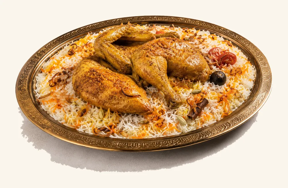 Roasted chicken quarters over saffron Mandi rice on a brass platter
